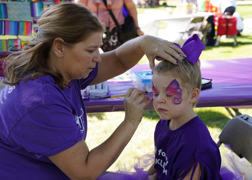 Harper Klemm, 6, of Clayton has her face painted by Michelle Miller from Masquerades of Adrian during the Walk to End Alzheimer's Oct. 2, 2022.