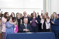 Surrounded by DFL legislators, Minnesota Gov. Tim Walz, center, signs a bill to add a "fundamental right" to abortion access into state law on Tuesday, Jan. 31, 2023, St. Paul, Minn. Walz's signature makes Minnesota the sixteenth state to spell out a right to abortion access in its law books or constitution, and the first state Legislature to take such action since Roe v. Wade was overturned in June 2022. (Glen Stubbe/Star Tribune via AP)