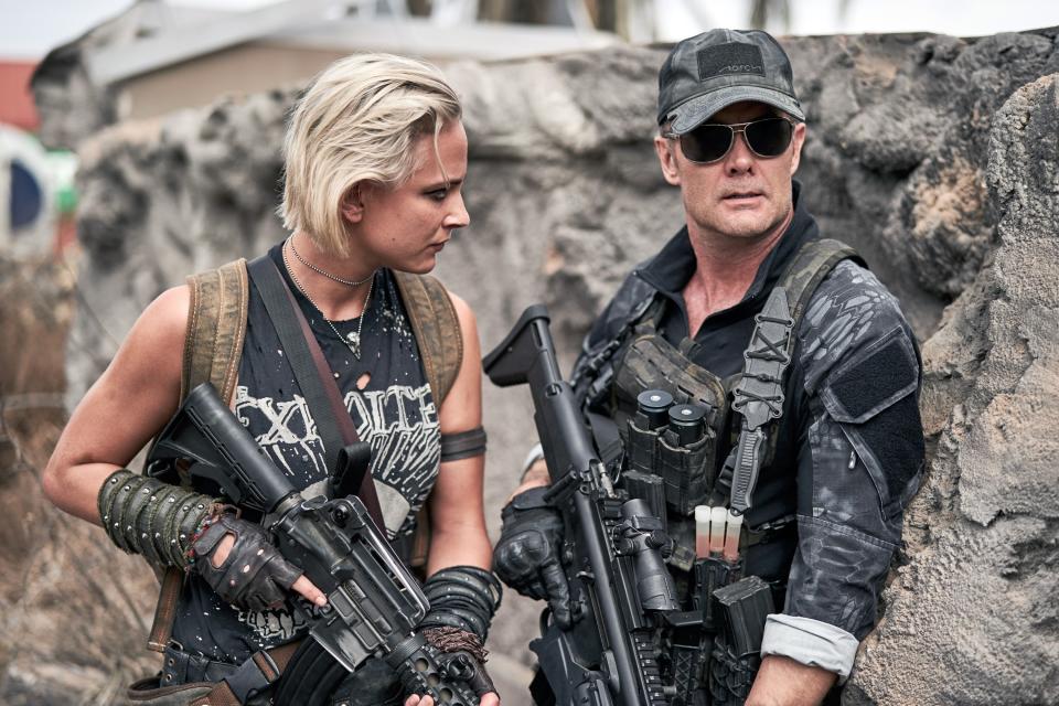 Lilly holds a gun and stares at Martin who is also holding a gun