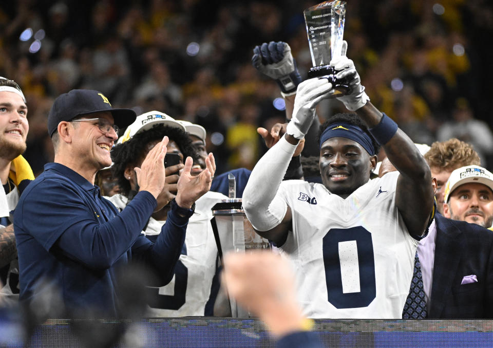 Dec. 2, 2023; Indianapolis, Indiana; Michigan Wolverines head coach Jim Harbaugh celebrates with MVP defensive back <a class="link " href="https://sports.yahoo.com/ncaaf/players/299576" data-i13n="sec:content-canvas;subsec:anchor_text;elm:context_link" data-ylk="slk:Mike Sainristil;sec:content-canvas;subsec:anchor_text;elm:context_link;itc:0">Mike Sainristil</a> (0) after winning the Big Ten Championship game against the Iowa Hawkeyes at Lucas Oil Stadium. Robert Goddin-USA TODAY Sports