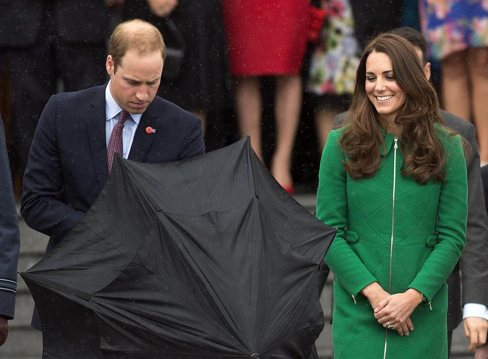 Britain's Prince William opens an umbrella for himself and his wife Catherine, Duchess of Cambridge, during a walkabout in Cambridge