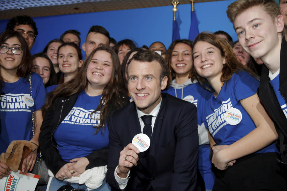 French President Emmanuel Macron poses with youths after he spoke at the opening of the International Agriculture Fair, in Paris, France, Saturday, Feb. 23, 2019. Macron pledged to protect European farming standards and culinary traditions threatened by aggressive foreign trade practices that see food as a "product like any other." (Charles Platiau/Pool Photo via AP)