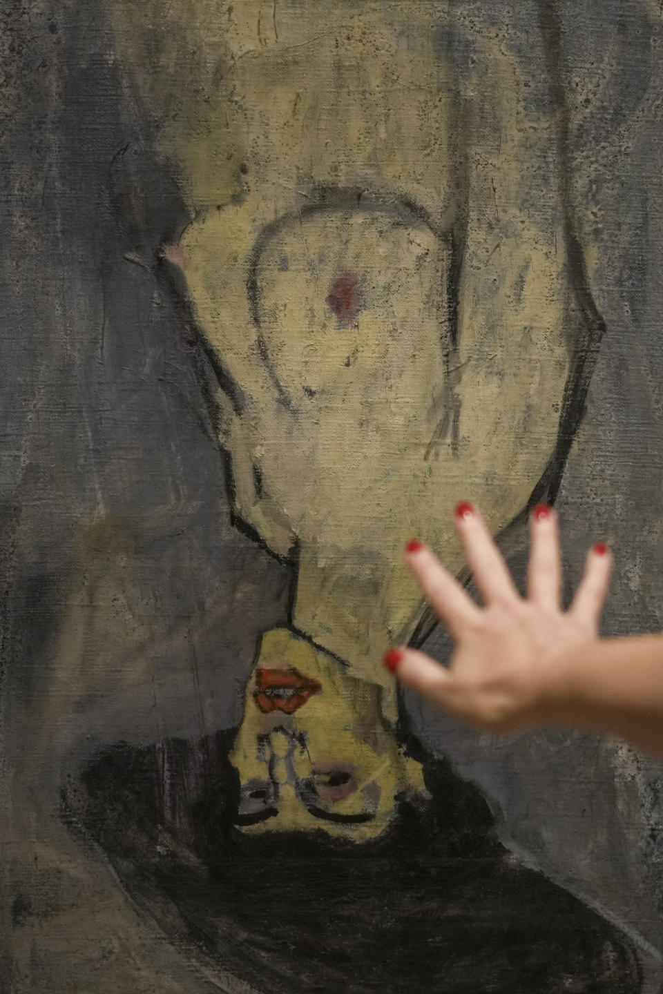 Inna Berkowits, an art historian at the Haifa University's Hecht Museum, explains about Amadeo Modigliani's 1908 "Nude with a Hat," hung upside down because another painting by him, "Maud Abrantes," on the reverse side of the same canvas is oriented correctly, while on display at Haifa University's Hecht Museum in Haifa, Israel, June 28, 2022. Curators at the museum using x-ray technology have discovered three previously unknown sketches by the celebrated 20th century artist hiding beneath the surface of the painting. (AP Photo/Ariel Schalit)