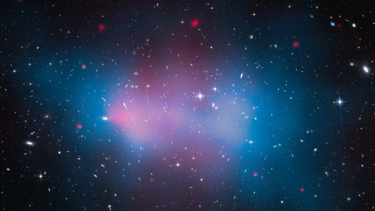  A view of space with blue and pink hazes overlaying lots of stars and galaxies. 