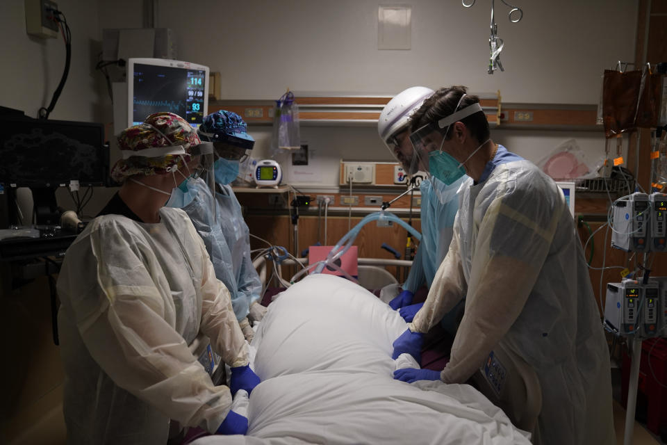 FILE - In this Dec. 22, 2020, file photo, medical workers prepare to manually prone a COVID-19 patient in an intensive care unit at Providence Holy Cross Medical Center in the Mission Hills section of Los Angeles. California surpassed 25,000 coronavirus deaths since the start of the pandemic, reporting the grim milestone Thursday, Dec. 31, 2020, as it continues to face a surge that has swamped hospitals and pushed nurses and doctors to the breaking point as they brace for an anticipated surge after the holidays. (AP Photo/Jae C. Hong, File)