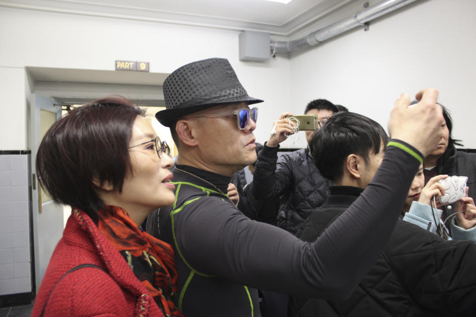 Chinese comedian Zhou Libo, center, stands with his wife Hu Jie, left, as he shoots a video of his lawyer, with reporters from Chinese media outlets outside a courtroom in Mineola, N.Y., on Long Island where Zhou pleaded not guilty to drug and weapon charges. The comedian and former judge on the "China's Got Talent" television program was arrested during a traffic stop on Jan. 19. Police said he had been driving erratically and when they stopped him said they noticed a shoulder holster in the back seat and found a loaded pistol and two plastic bags containing crack cocaine in a backpack. (AP Photo/Frank Eltman)