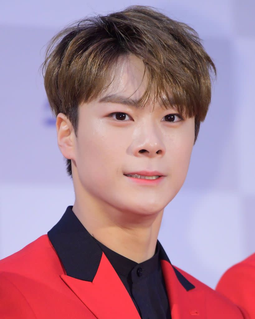 k pop star moonbin attending music awards wearing a red jacket