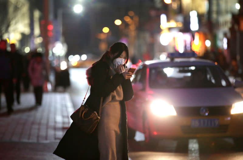 A woman holds the mask at a street in Beijing