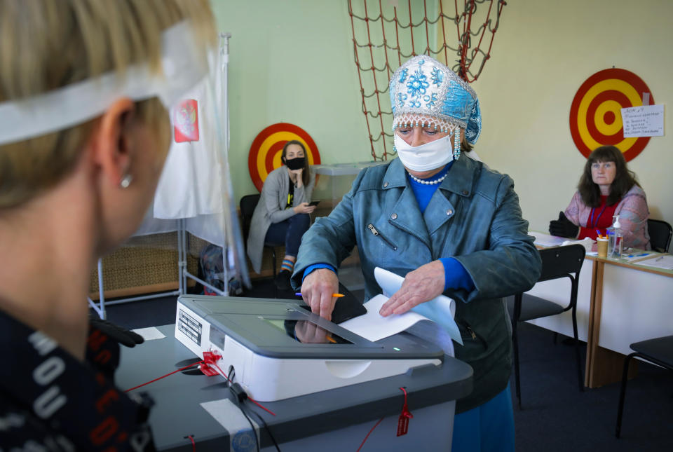 A woman wearing a face mask to protect against coronavirus infection casts her ballot at a poling station during Leningrad region's governor and municipal elections in Luppolovo village, outside St.Petersburg, Russia, Sunday, Sept. 13, 2020. Leningrad region is the territory surrounding St. Petersburg. The elections are held to choose governors and legislators in about half of Russia's regions. (AP Photo/Dmitri Lovetsky)