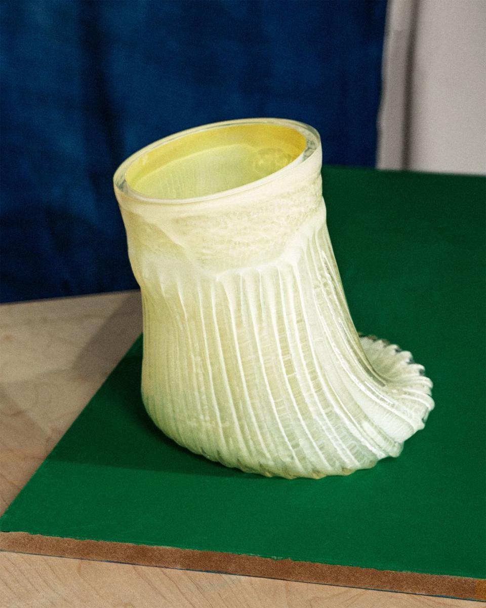 a white vase that has a slinky fabric looking appearance on a green surface
