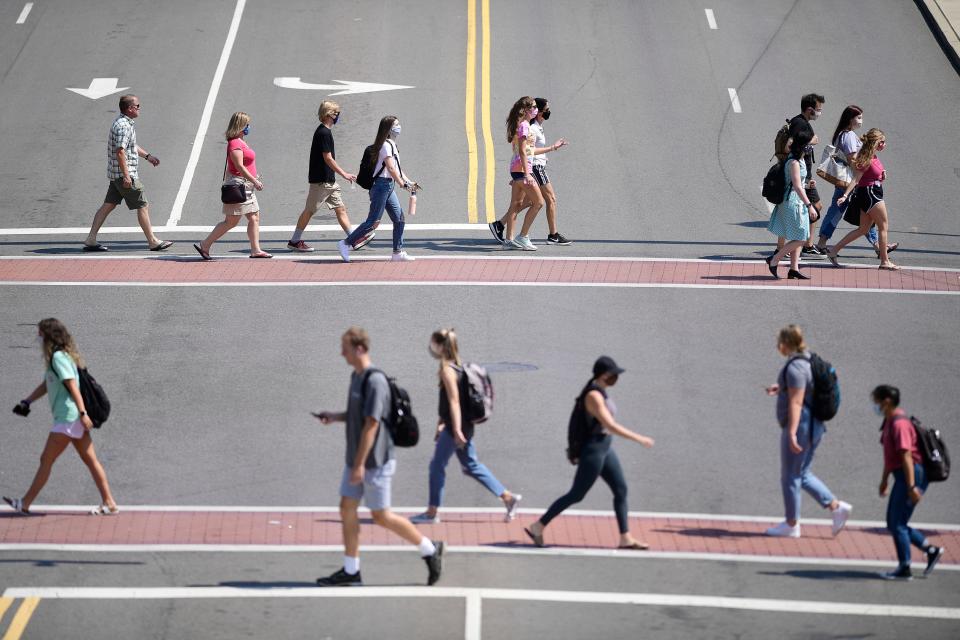 Students cross Cumberland Avenue and Volunteer Boulevard on the University of Tennessee campus in Knoxville on Tuesday. The school has seen a recent uptick in coronavirus cases.