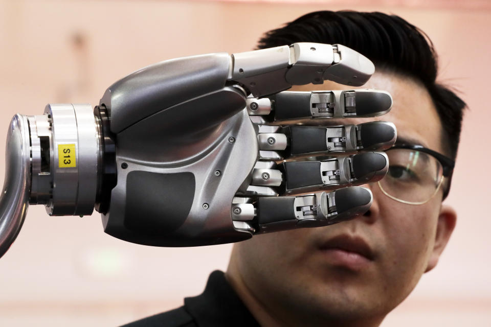 FILE - In this Aug. 23, 2017, file photo, a visitor looks at a robotic hand powered by Kinfinity Glove, developed by the German Aerospace Center, on display at the World Robot Conference at the Yichuang International Conference and Exhibition Centre in Beijing. China’s government has appealed to Washington to accept its industrial progress after U.S. intelligence officials said Beijing helps to steal and copy foreign technologies. (AP Photo/Andy Wong)