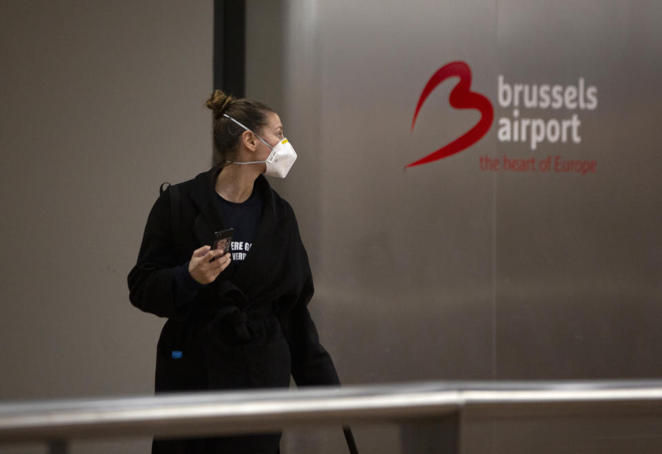 A woman wears a protective mask as she arrives at Brussels International Airport in Brussels, Friday, March 13, 2020. European Union interior ministers on Friday were trying to coordinate their response to the COVID-19 coronavirus as the number of cases spreads throughout the 27-nation bloc and countries take individual measures to slow the disease down. For most people, the new coronavirus causes only mild or moderate symptoms, such as fever and cough. For some, especially older adults and people with existing health problems, it can cause more severe illness, including pneumonia. (AP Photo/Virginia Mayo)