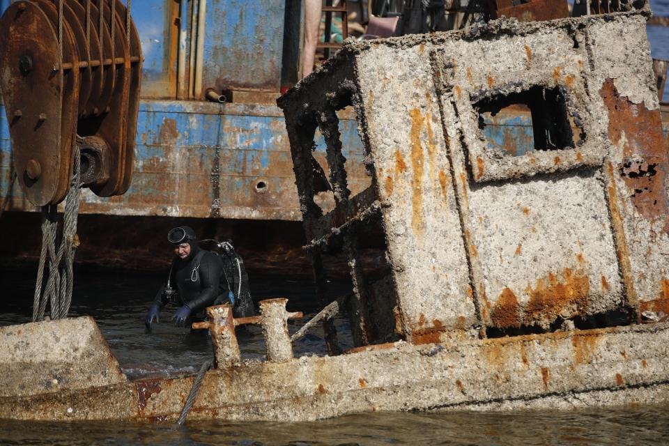 A diver checks an old vessel during a shipwreck raising operation, on Salamina island, west of Athens, on Friday, Nov. 8, 2019. Greece this year is commemorating one of the greatest naval battles in ancient history at Salamis, where the invading Persian navy suffered a heavy defeat 2,500 years ago. But before the celebrations can start in earnest, authorities and private donors are leaning into a massive decluttering operation. They are clearing the coastline of dozens of sunken and partially sunken cargo ships, sailboats and other abandoned vessels. (AP Photo/Thanassis Stavrakis)