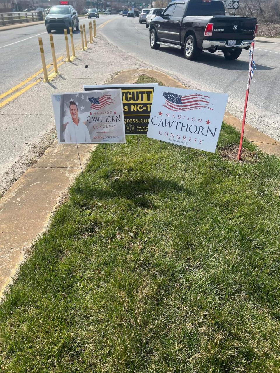 Two of Madison Cawthorn's campaign signs obscure the view of Rod Honeycutt's sign earlier this week along South Main Street in Hendersonville.