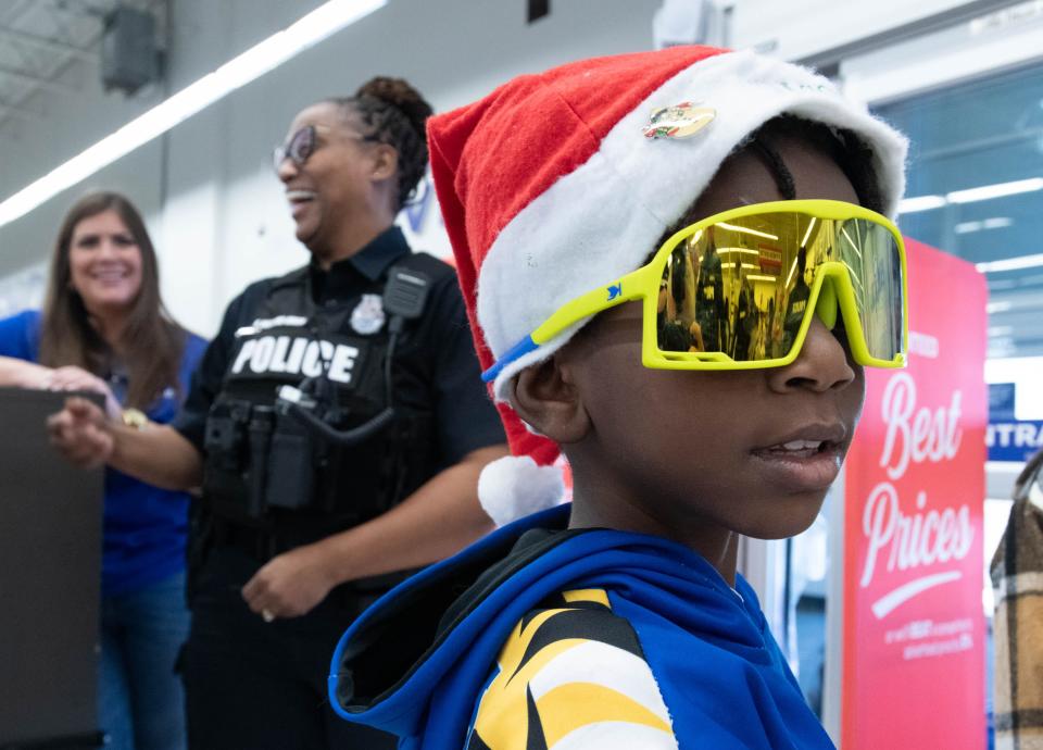 Christian Smith, 8, tries out his new sunglasses during the Shop with a Cop shopping spree at the Academy Sports + Outdoors in Pensacola on Thursday, Dec. 21, 2023.