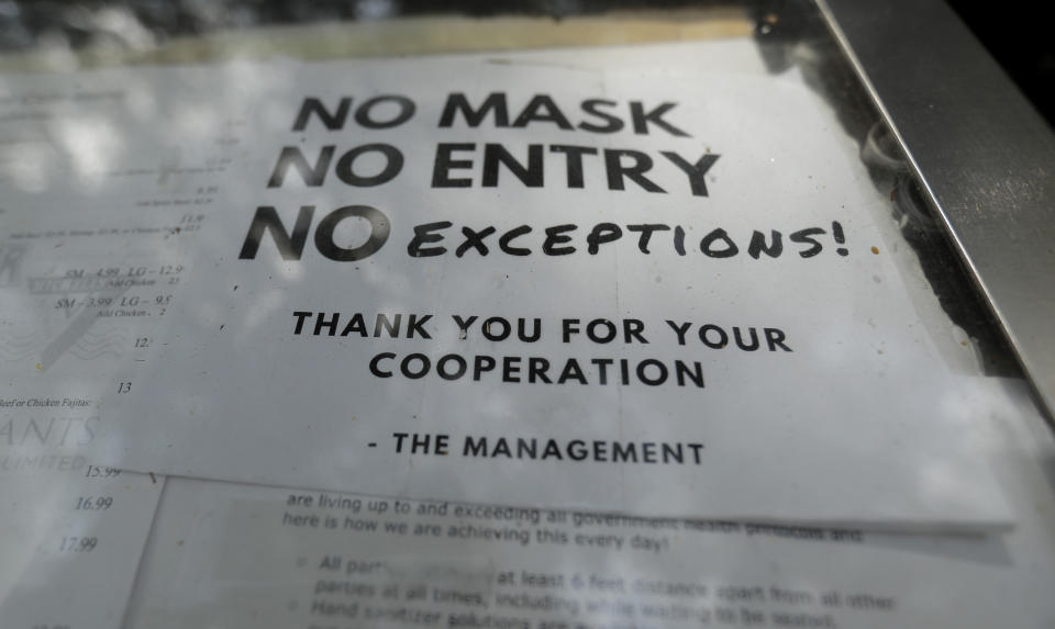 A sign requiring face masks to protect against the spread of COVID-19 is seen at a restaurant, Tuesday, July 7, 2020, in San Antonio. Texas Gov. Greg Abbott has declared masks or face coverings must be worn in public across most of the state as local officials across the state say their hospitals are becoming increasingly stretched and are in danger of becoming overrun as cases of the coronavirus surge. (AP Photo/Eric Gay)
