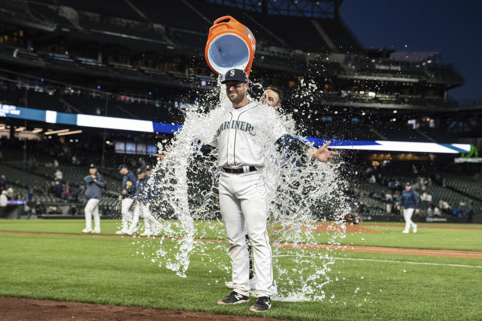 Seattle Mariners' Tom Murphy stands of the field as teammate AJ Pollock dumps water onto him after the Mariners defeated the Texas Rangers 5-0 in a baseball game Tuesday, May 9, 2023, in Seattle. (AP Photo/Stephen Brashear)