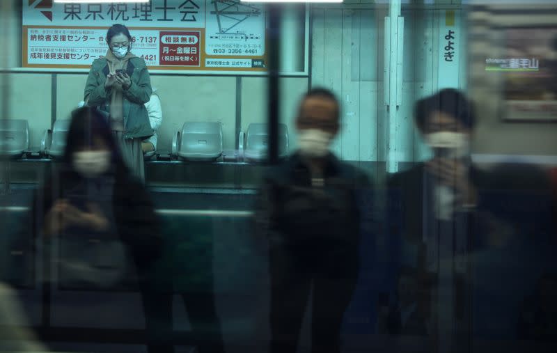 Woman, wearing protective face mask, following an outbreak of the coronavirus, waits for her train at Yoyogi station in Tokyo