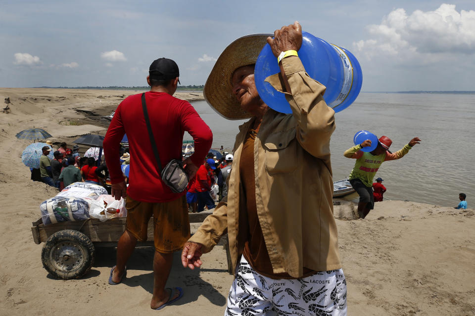 FILE - A resident of a riverside community carries a container of drinking water from an aid distribution due to the ongoing drought in Careiro da Varzea, Amazonas state, Brazil, Tuesday, Oct. 24, 2023. On Tuesday, the municipality distributed emergency kits using an improvised barge originally designed to transport cattle. (AP Photo/Edmar Barros, File)