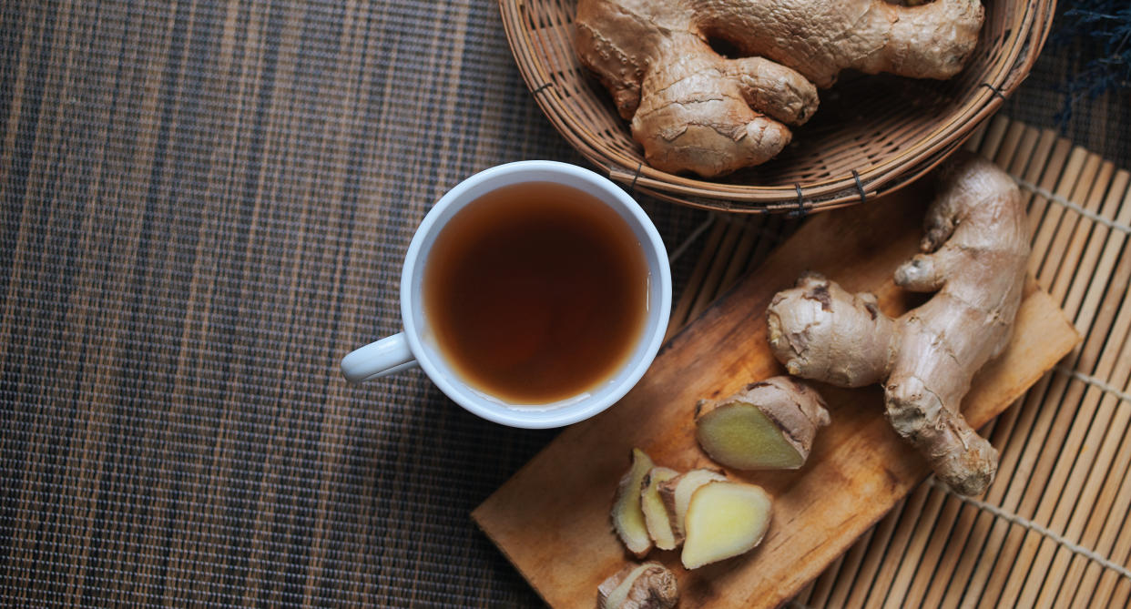 a cup of ginger tea alongside ginger root