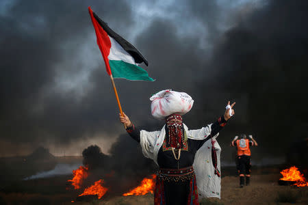 A woman holds a Palestinian flag during a protest calling for lifting the Israeli blockade on Gaza and demand the right to return to their homeland, at the Israel-Gaza border fence, east of Gaza City September 14, 2018. REUTERS/Mohammed Salem