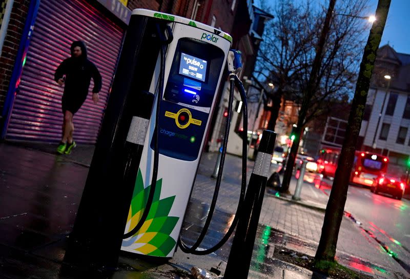 FILE PHOTO: A man runs past a BP (British Petroleum) EV (Electric Vehicle) charge point in London