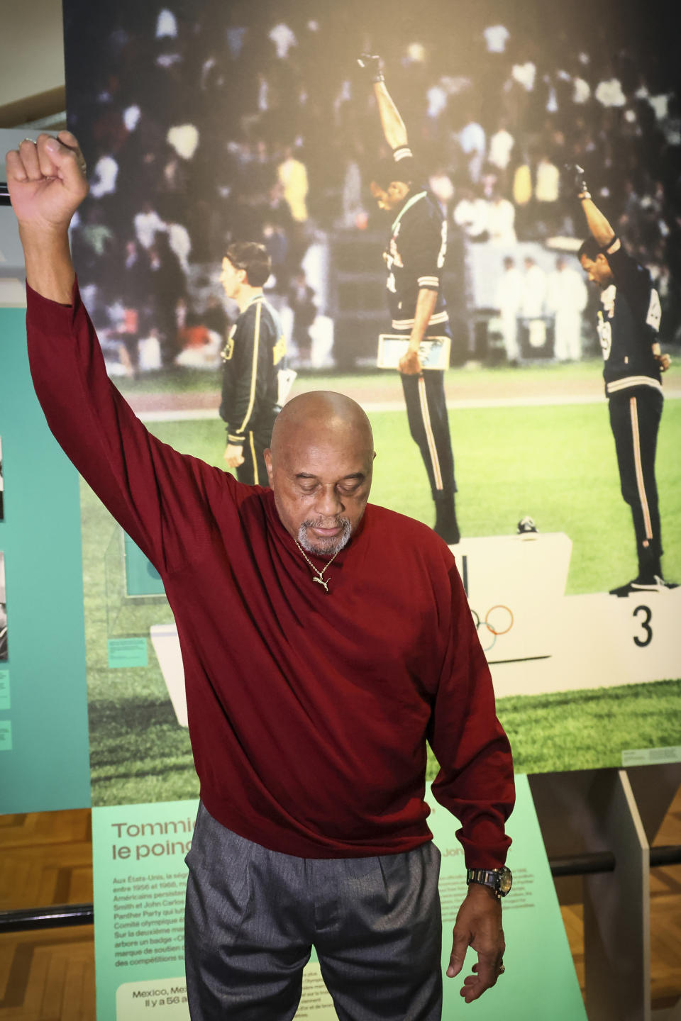 American former track and field athlete Tommie Smith reenacts his gesture in front of the photograph of him at the 1968 Olympics, at the Immigration Museum, Tuesday, June 11, 2024 in Paris. Smith and John Carlos gave a black-gloved salute on the medal stand at the 1968 Olympics in Mexico City. (AP Photo/Thomas Padilla)