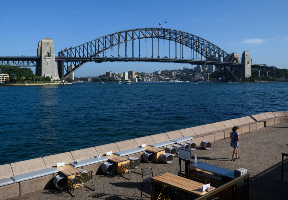 A lone woman walks through a quiet Opera Bar in front of the Sydney Harbour Bridge. Source: AAP