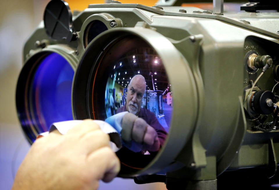 Gary Wagner, of Elbit Systems of America, cleans the lens of a long range thermal imaging targeting system at the 8th annual Border Security Expo, Tuesday, March 18, 2014 in Phoenix. The two day event will feature panel discussions, sharing intelligence, and exhibitors displaying high-tech wares aimed at securing lucrative government contracts and private sales. (AP Photo/Matt York)