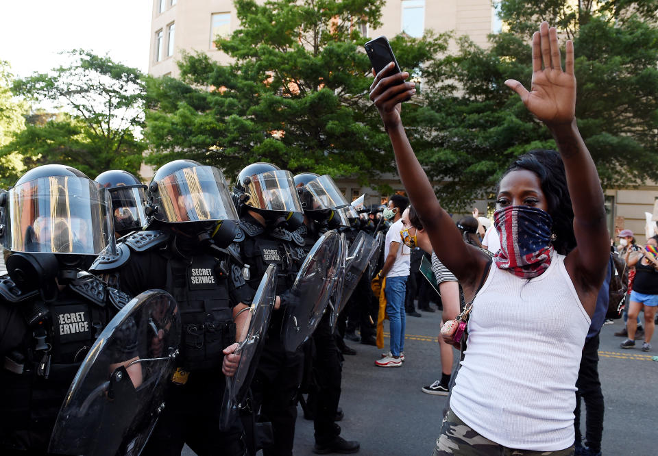 A protester stands, arms in the air, in front of a row of officers during a demonstration near the White House on June 1. (Photo: OLIVIER DOULIERY/AFP via Getty Images)