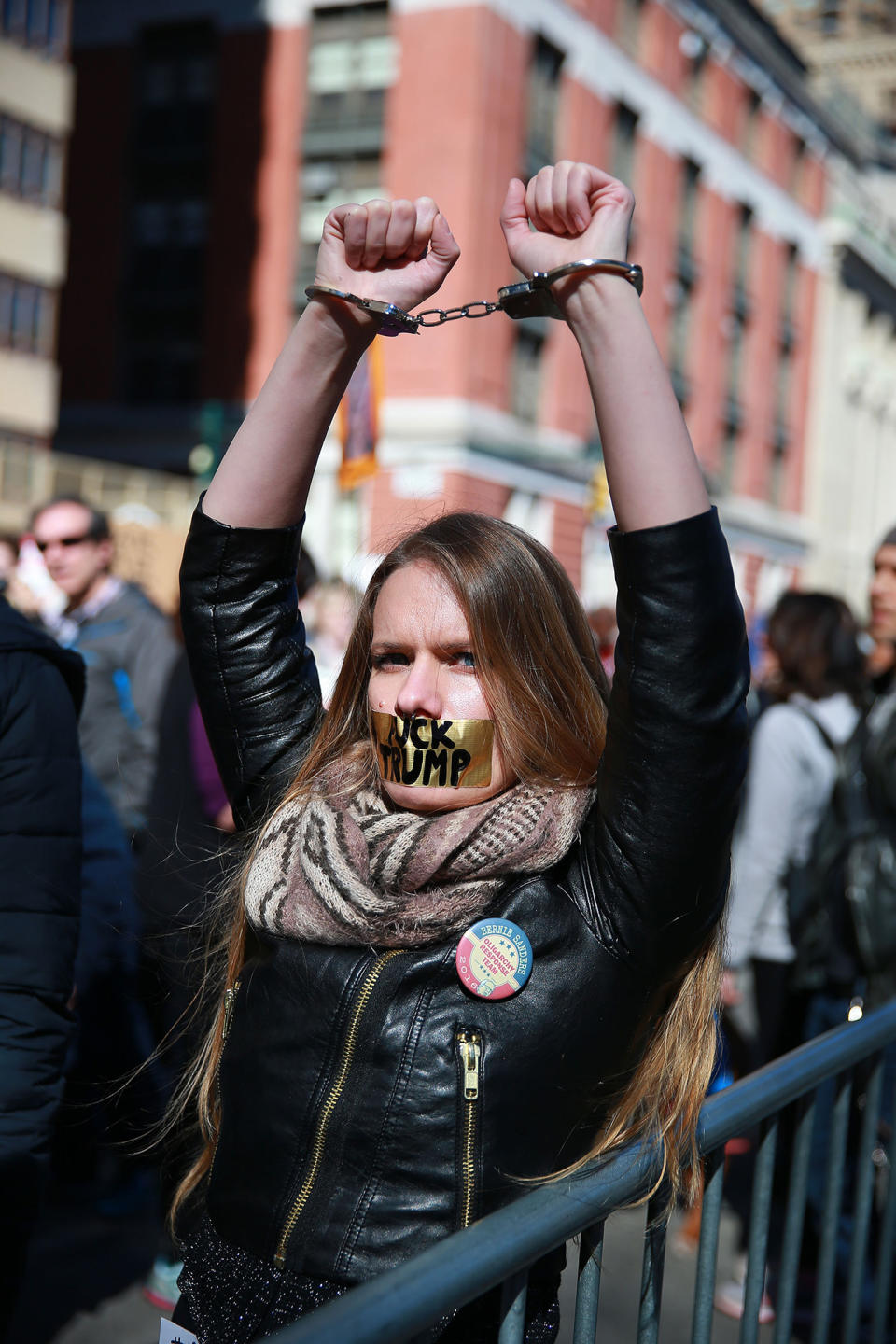 <p>A young woman wears handcuffs and has her mouth taped shut with the words “F*** TRUMP” inside police barricades at the “Not My President’s Day” rally at Central Park West in New York City on Feb. 20, 2017. (Gordon Donovan/Yahoo News) </p>