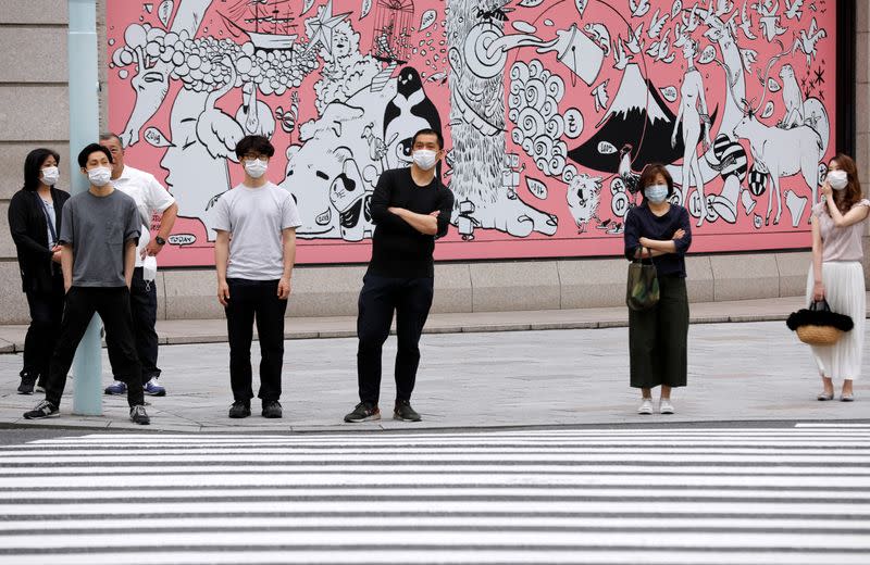 Personas con mascarillas esperan para cruzar una calle en un distrito comercial en Tokio, Japón, el 25 de mayo de 2020