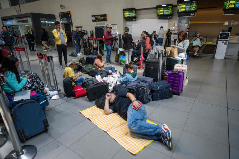 Personas tiradas en el piso luego de que sus vuelos fueran cancelados en el aeropuerto internacional El Dorado de Bogotá el 28 de febrero de 2023