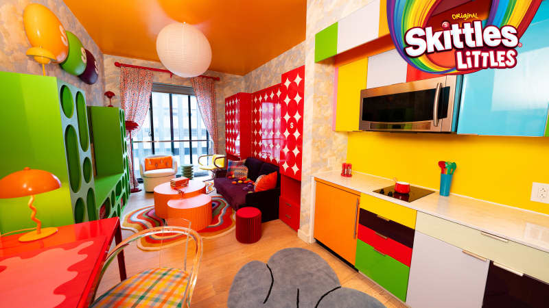 Colorful living room seen from kitchen in Skittles Littles apartment, designed by Dani Klaric.