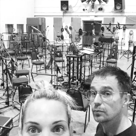 a man and a woman taking a selfie in a room with tables and chairs