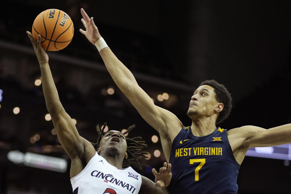 Cincinnati guard Jizzle James, left, shoots under pressure from West Virginia center Jesse Edwards (7) during the second half of an NCAA college basketball game Tuesday, March 12, 2024, in Kansas City, Mo. Cincinnati won 90-85. (AP Photo/Charlie Riedel)