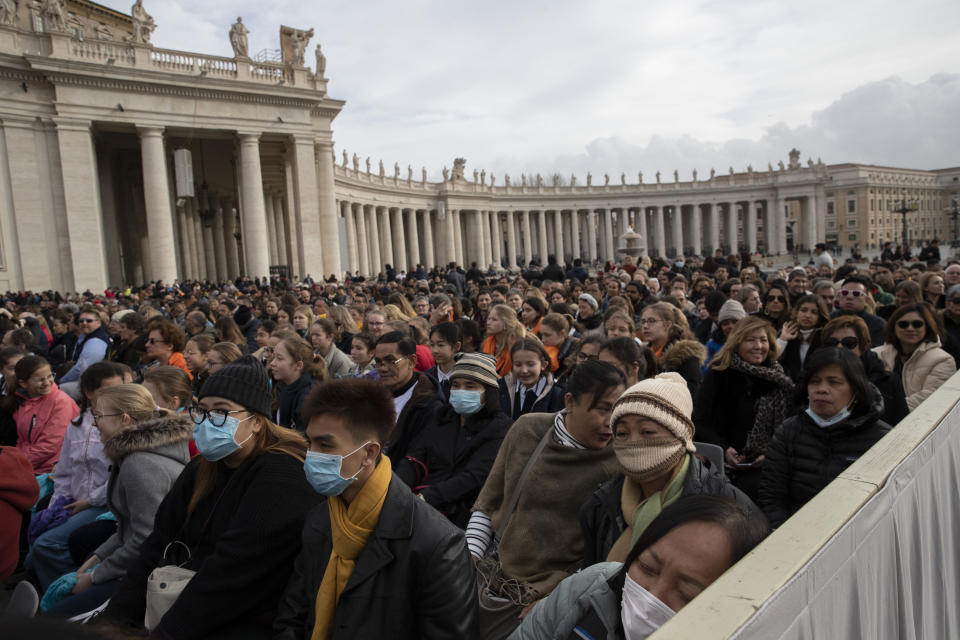 Faithful wear face masks as they wait for Pope Francis arrival in St. Peter's Square at the Vatican for his weekly general audience, Wednesday, Feb. 26, 2020. (AP Photo/Alessandra Tarantino)