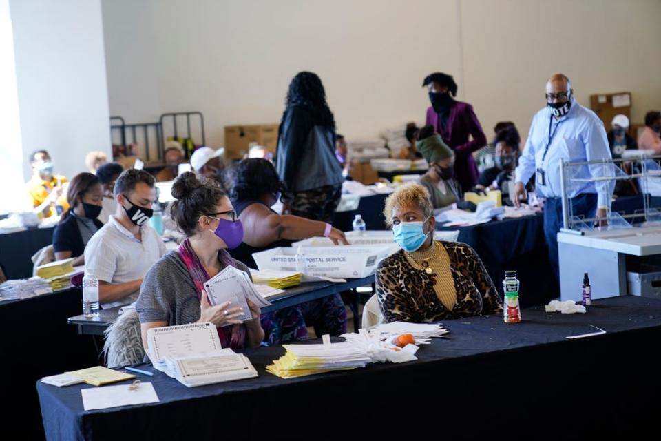 An election worker handles ballots as vote counting in the general election continues at State Farm Arena on Thursday, Nov. 5, 2020, in Atlanta.