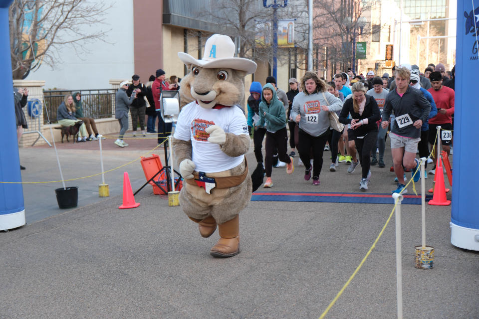 Ruckus of the Amarillo Sod Poodles leads runners past the start line Saturday at the 2023 Center City Mural Run in downtown Amarillo.