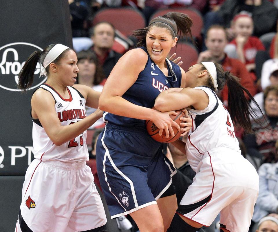 Connecticut's Stefanie Dolson, center, battles Louisville's Tia Gibbs, Left, and Bria Smith for a rebound during the first half of an NCAA college basketball game Monday, March 3, 2014, in Louisville, Ky. (AP Photo/Timothy D. Easley)