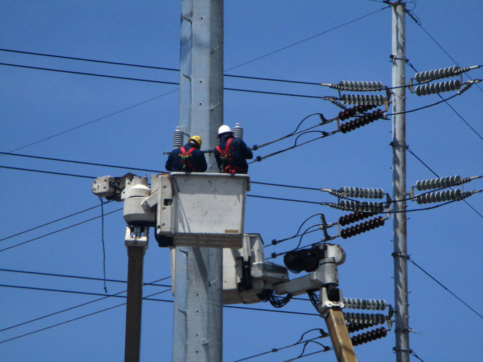 Filipino linemen perform routine maintenance tasks on an electric pole at an intersection in the financial district of Makati City, Philippines. (Photo: Getty Images)