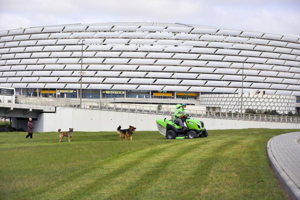 ARCHIVO - En esta foto del miércoles 18 de marzo de 2020, una cuadrilla de mantenimiento poda al césped afuera del Estadio Olímpico en Bakú, Azerbaiyán, una de las sedes de la Eurocopa. (AP Foto/Aziz Karimov, archivo)