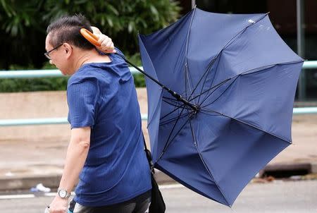 A man struggles with an umbrella while walking against strong wind as Typhoon Nida hits Hong Kong, China August 2, 2016. REUTERS/Tyrone Siu