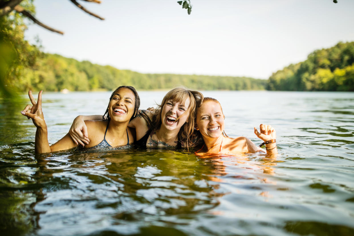 Portrait of three young women together in lake. Group of young female friends enjoying swimming together in lake.