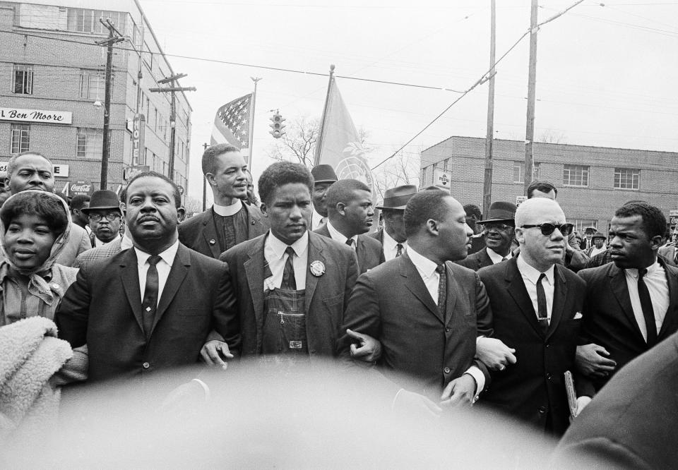 FILE - In this March 17, 1965, file photo, Dr. Martin Luther King Jr., fourth from left, foreground, locks arms with his aides as he leads a march of several thousands to the courthouse in Montgomery, Ala. From left are: an unidentified woman, Rev. Ralph Abernathy, James Foreman, King, Jesse Douglas Sr., and John Lewis. Lewis, who carried the struggle against racial discrimination from Southern battlegrounds of the 1960s to the halls of Congress, died Friday, July 17, 2020. (AP Photo/File)