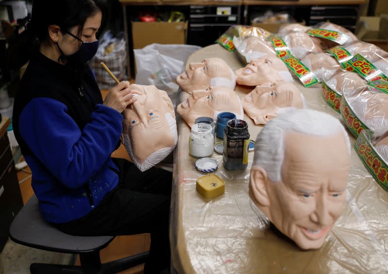 A worker of Ogawa Studios gives the final touches to a mask depicting U.S. President-elect Joe Biden is seen between the Biden mask and mask of President Donald Trump, in Saitama, Japan