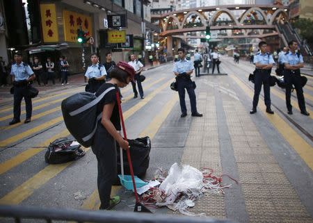 A pro-democracy protester sweeps a street after policemen removed some barricades, at a protest site at the commercial area of Causeway Bay in Hong Kong October 14, 2014. REUTERS/Carlos Barria