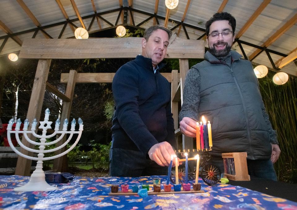 Temple Beth-El Rabbi Joel Fleekop, left, and B'nai Israel Rabbi David Cohen-Henriquez light menorahs during a party Wednesday, Dec. 21, 2022.