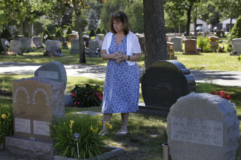 FILE - In this Tuesday, June 19, 2018 file photo, Cheryl Juaire, of Marlborough, Mass., stands at her son's grave, in Chelmsford, Mass. Victims of opioid addiction weren’t in the room when big decisions were hammered out in OxyContin maker Purdue Pharma’s proposal to settle claims over its role in the U.S. opioid crisis. Cheryl Juaire lost her 23-year-old son to a heroin overdose after he became addicted to prescription painkillers. (AP Photo/Steven Senne, File)